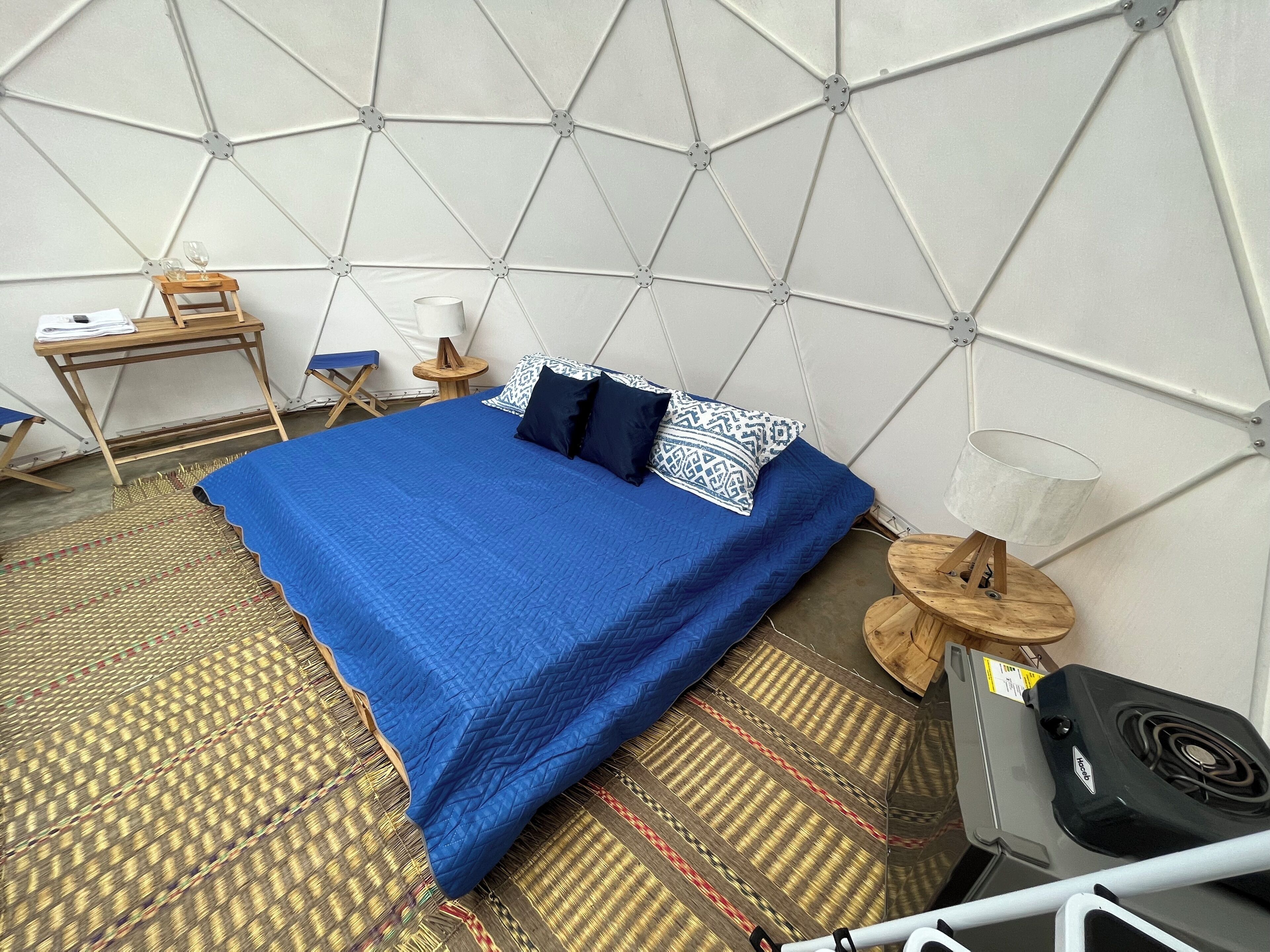 A room with a bed, a small desk, a chair, a lamp, and a heater.