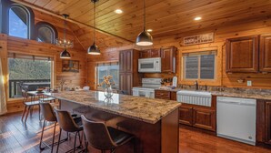 A spacious kitchen with wooden cabinets, a granite countertop, and a large island with bar stools. - Beautiful Views, Spacious, Hot Tub, Easy Access Roads, & Free Attractions! (Sevierville)