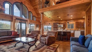 A spacious living room with a large window, a fireplace, and a cozy seating area. - Beautiful Views, Spacious, Hot Tub, Easy Access Roads, & Free Attractions! (Sevierville)