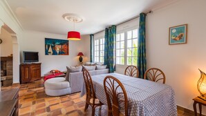 A cozy room with a bed, a sofa, a dining table with chairs, a TV, and a fireplace.