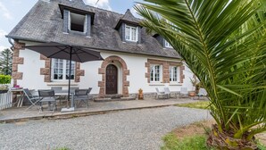 A house with a gravel driveway, a patio with outdoor furniture, and a palm tree.