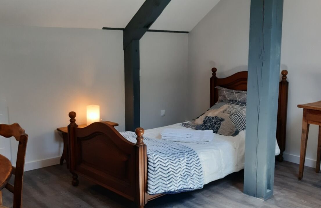 Une chambre à coucher avec un lit en bois, une table de chevet et une chaise.