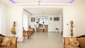 A reception area with a reception desk, chairs, and a hallway leading to other rooms. - Asumbi Resort  (Asumbi)