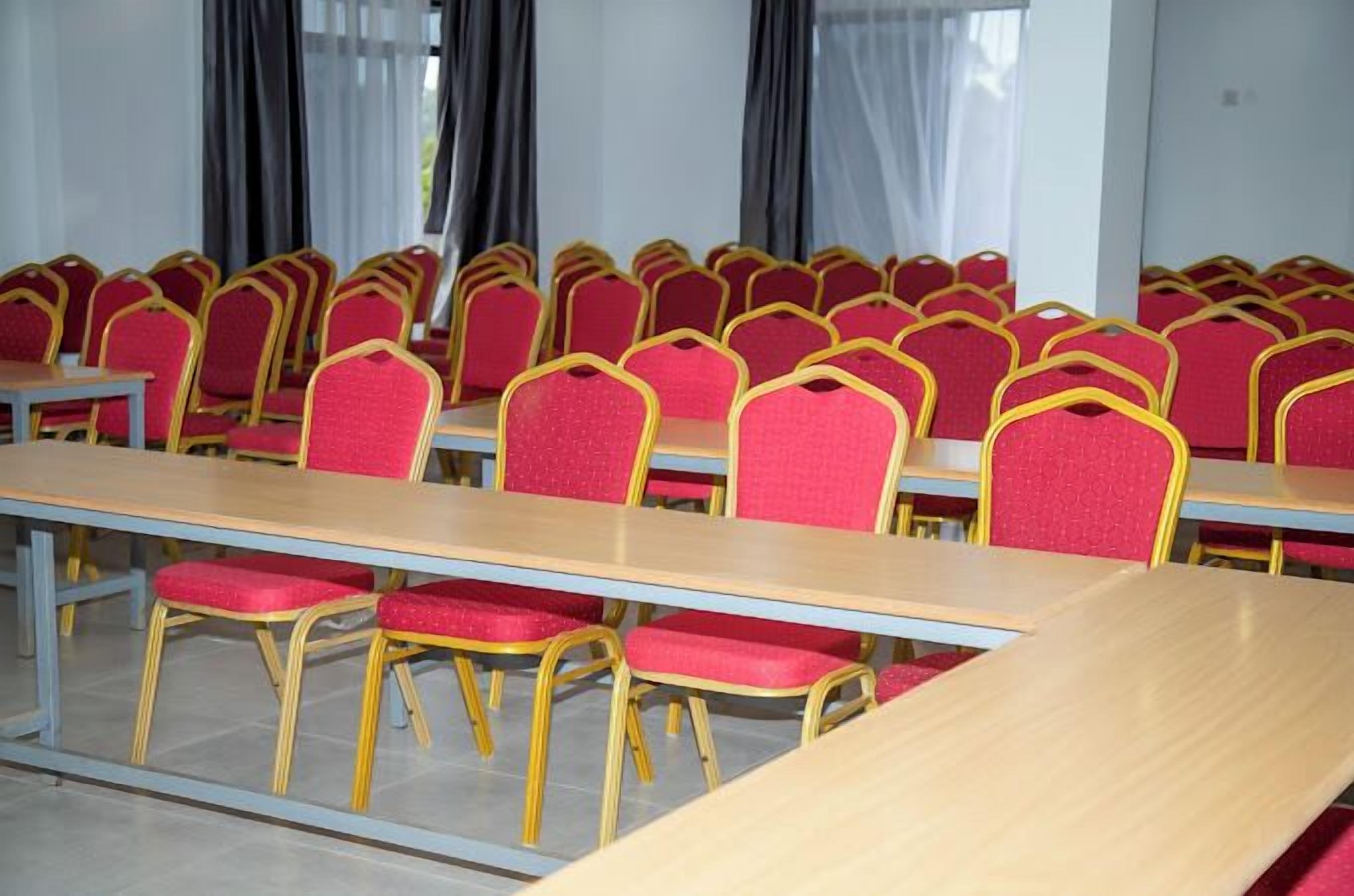 Une salle de conférence avec plusieurs tables et des chaises rouges.