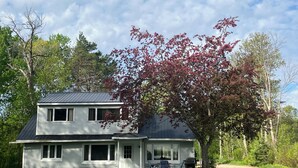 Ein zweistöckiges Haus mit Veranda, Garage und Rasen.