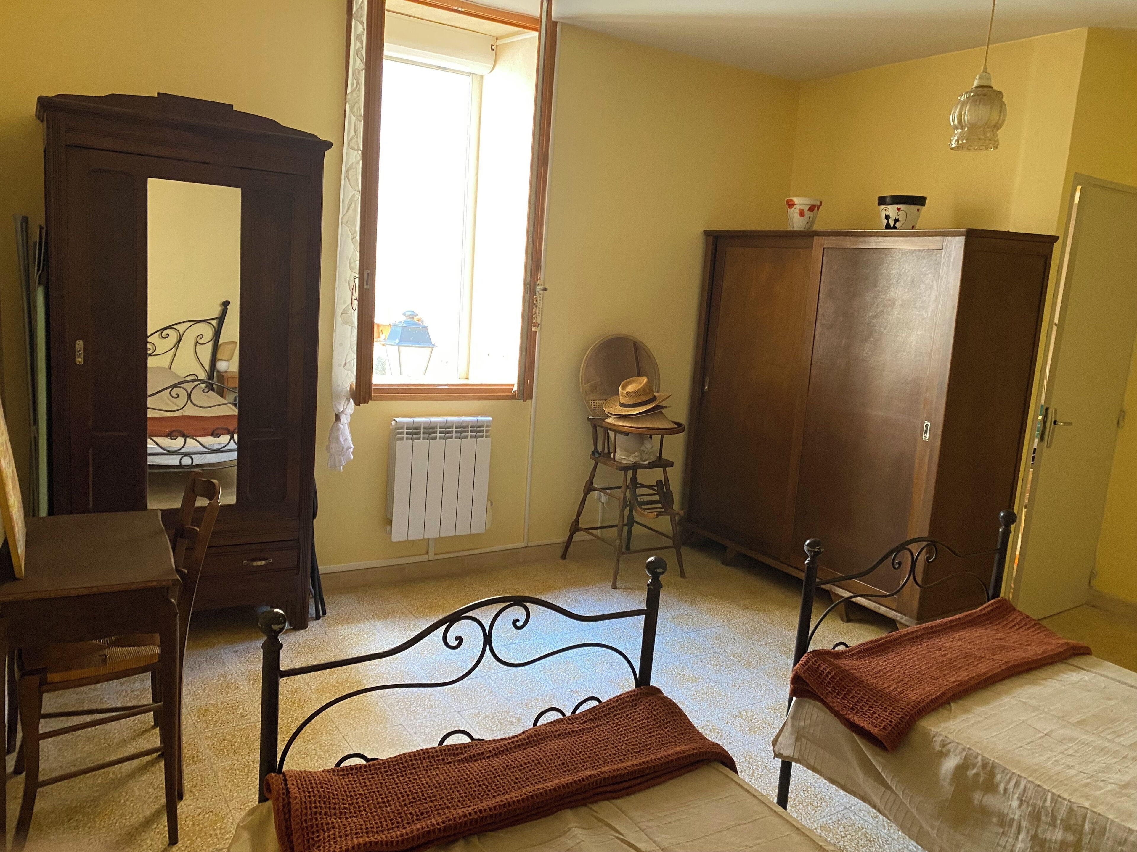 Een slaapkamer met een bed, een houten garderobe, een stoel, een radiator en een raam.