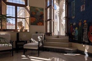 Una habitación con un ventanal grande, una silla, una mesa y una escalera que conduce a un piso superior.