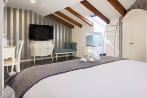 Un dormitorio con cama, televisión, cómoda, silla, sofá, escalera y armario.
