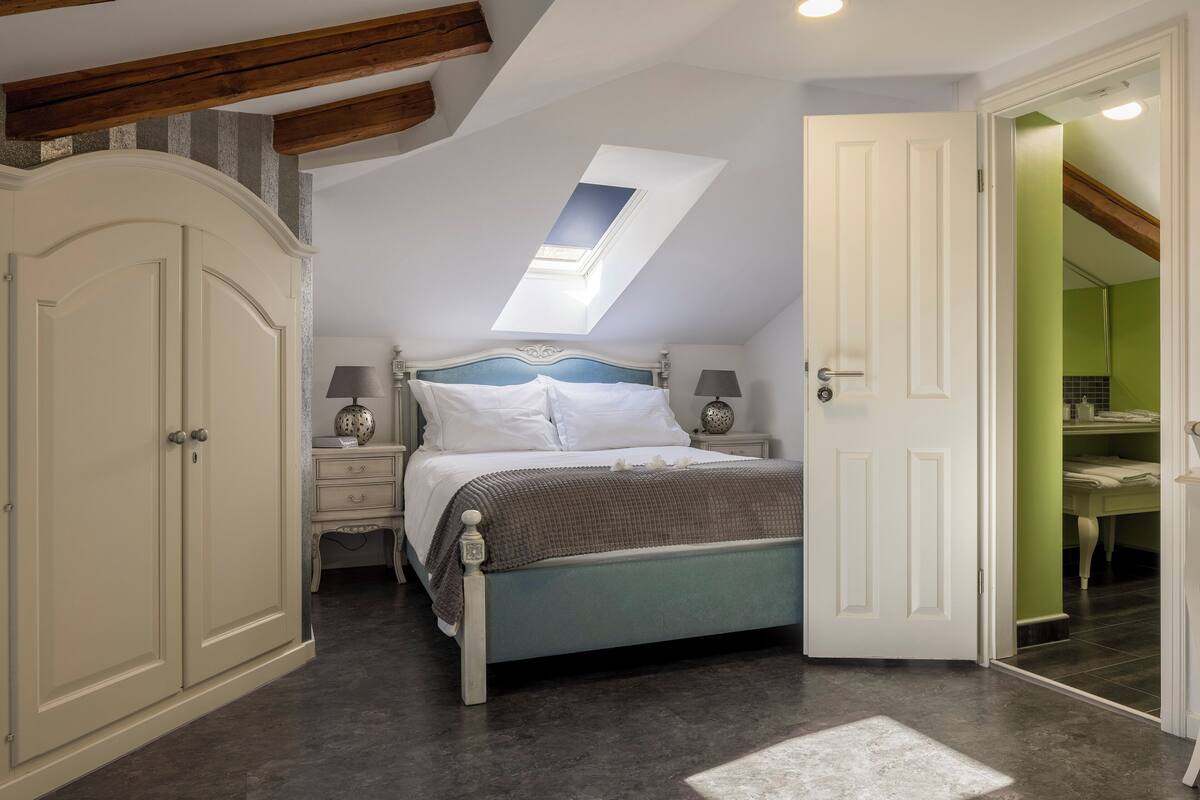 A bedroom with a skylight, a bed, bedside tables, and a wardrobe.