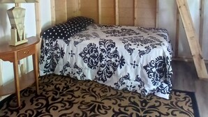 Una habitación acogedora con una cama litera, una alfombra estampada y una lámpara colgante.