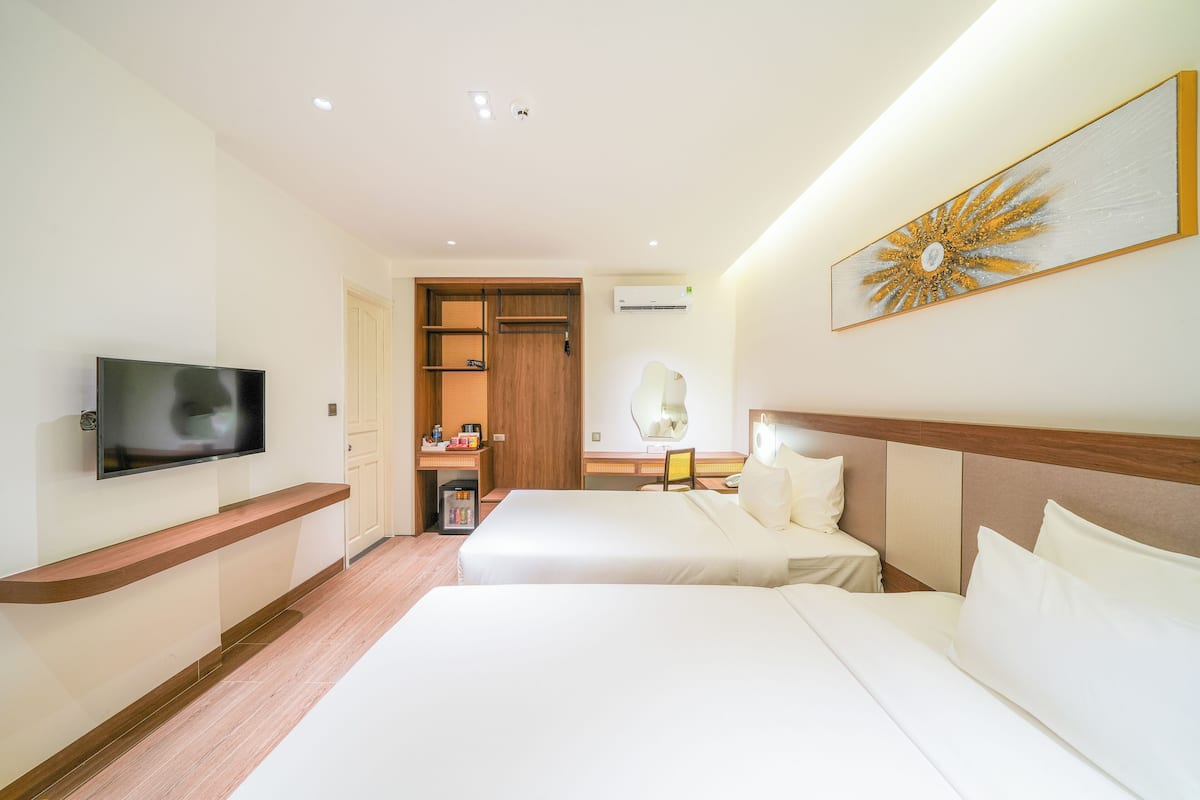 Une chambre d’hôtel avec deux lits, une télévision, une étagère en bois, une armoire et une œuvre d’art accrochée au mur.