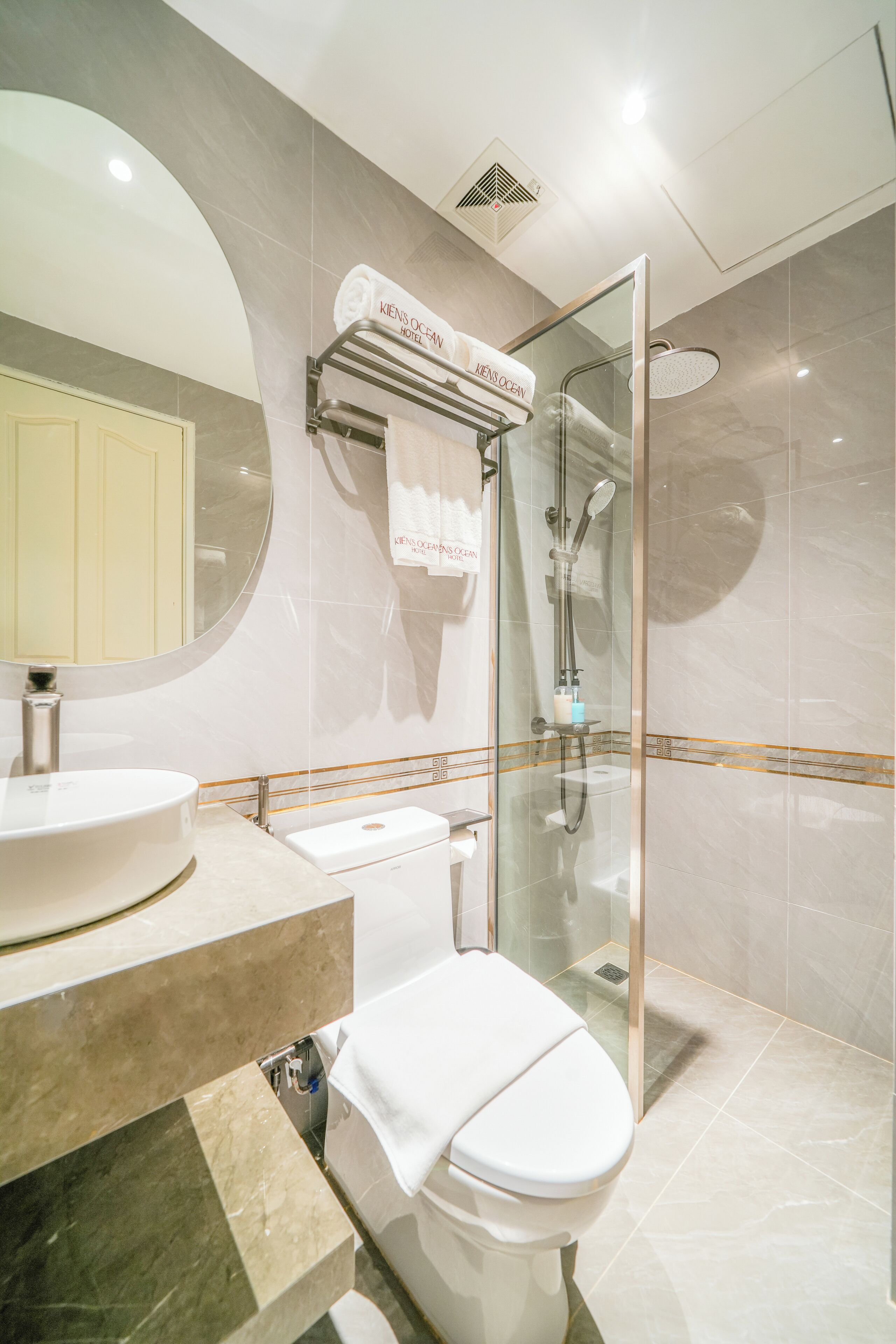 Une salle de bain moderne avec un lavabo rond, des toilettes et une douche à parois de verre.