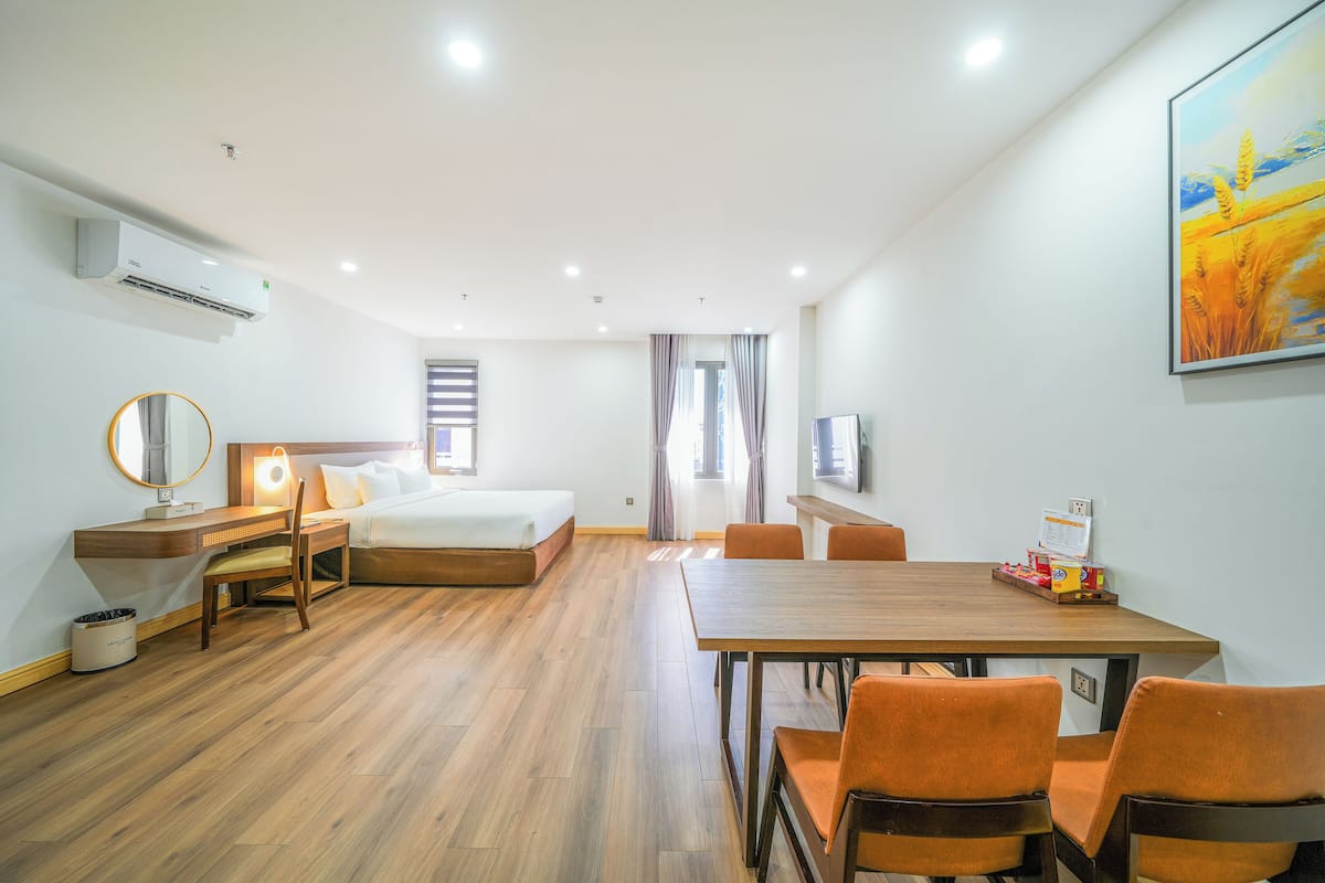 Une chambre d’hôtel comprenant un lit, un bureau, une chaise, une table à manger et un tableau au mur.