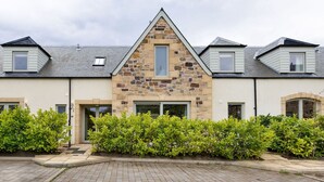 A row of modern houses with stone facades, a paved driveway, and well-maintained greenery.