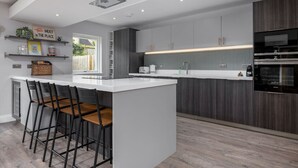 A modern kitchen with a central island, bar stools, built-in appliances, and a window providing natural light.