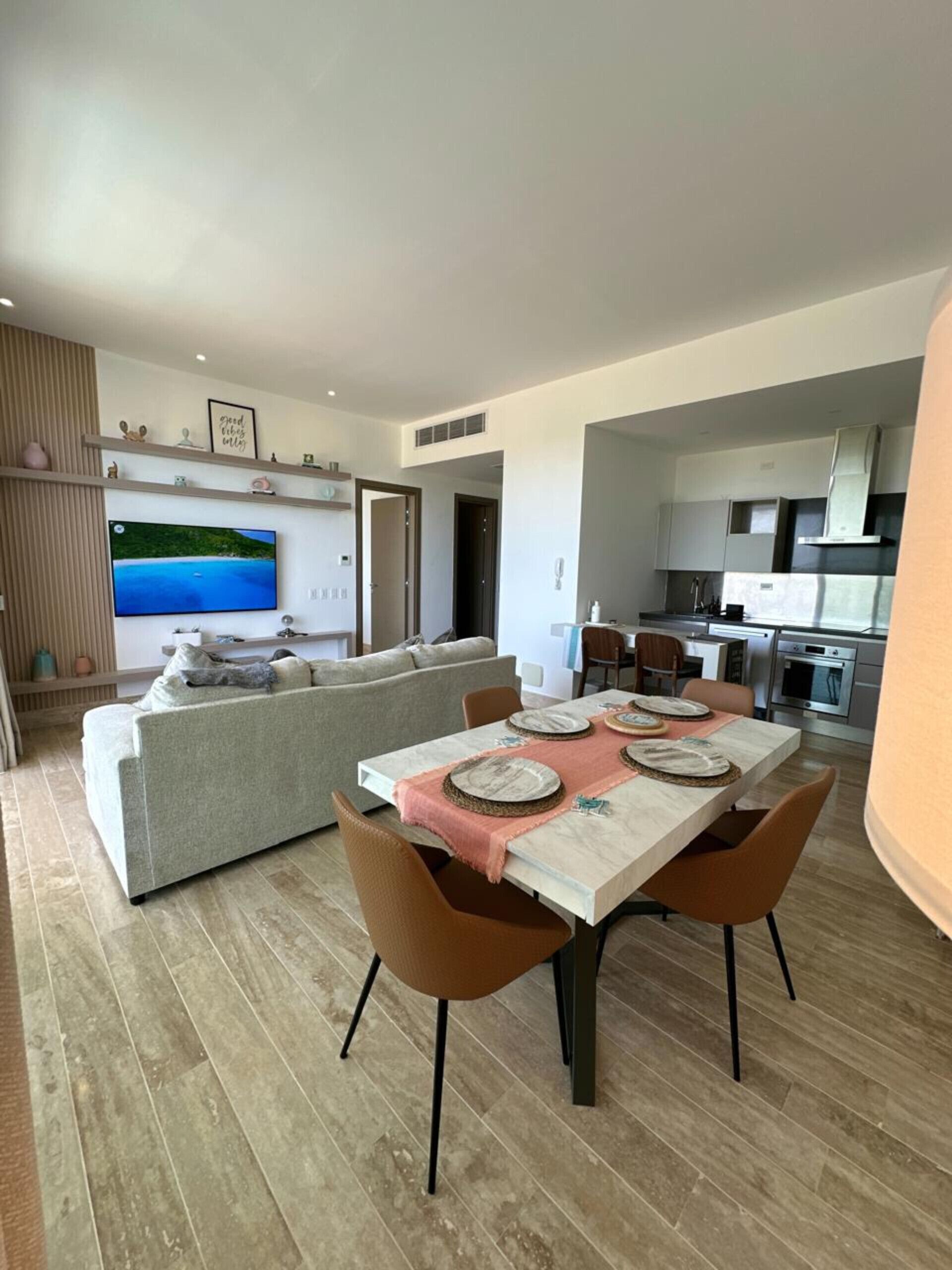 Un soggiorno moderno con zona pranzo, divano e cucina.