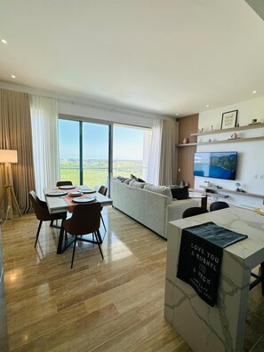A modern living room with a dining area, large windows, and a flat-screen TV. - 7 Mares B6 in Punta Cana (Punta Cana)