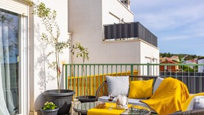A balcony with outdoor furniture, a potted plant, and a glass table.