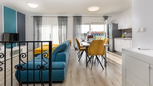 A modern apartment with a dining area, a sofa, and a kitchen.