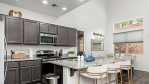 A modern kitchen with dark cabinets, a granite countertop, and a bar area with stools.