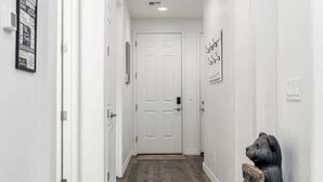 A hallway with wooden flooring, white walls, and a white door at the end.