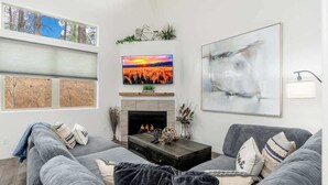 A living room with a fireplace, a television, and a large abstract painting.