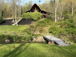 A cabin with a wooden deck and a staircase leading to a balcony.