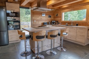 Eine moderne Küche mit einer zentralen Kochinsel, Barhocker, Edelstahlgeräten und Holzschränken.