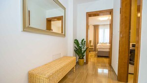 A hallway with a bench, a potted plant, and a mirror on the wall.