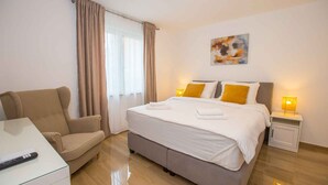 A hotel room with a bed, a sofa, a bedside table, and a lamp.