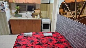 A compact room with a bed, kitchenette, and a small window.