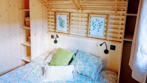 A wooden room with a bed, shelves, and framed botanical prints on the wall. - LE DOMAINE DE LA RICHE (Bioussac)