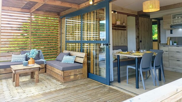 A cozy cabin with a wooden interior, a dining area with a table and chairs, and a sofa with cushions. - LE DOMAINE DE LA RICHE (Bioussac)