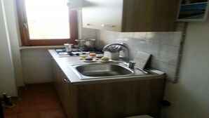 Una cocina compacta con fregadero, estufa y ventana.