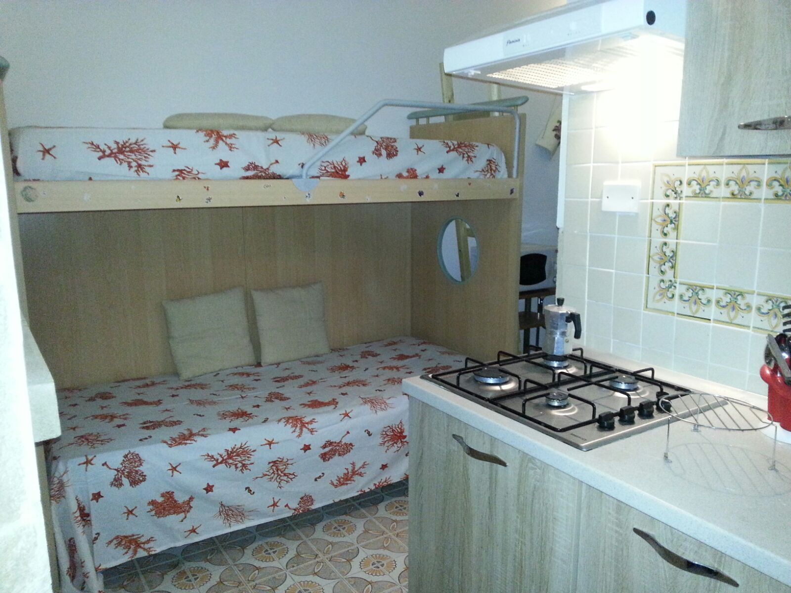 Una habitación compacta con literas, kitchenette y baño pequeño.