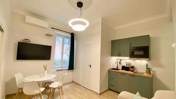 A compact living space with a dining area, kitchenette, and a sofa.
