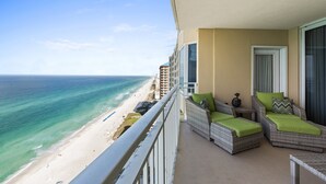 Un balcon doté de meubles en osier et offrant une vue sur la plage.