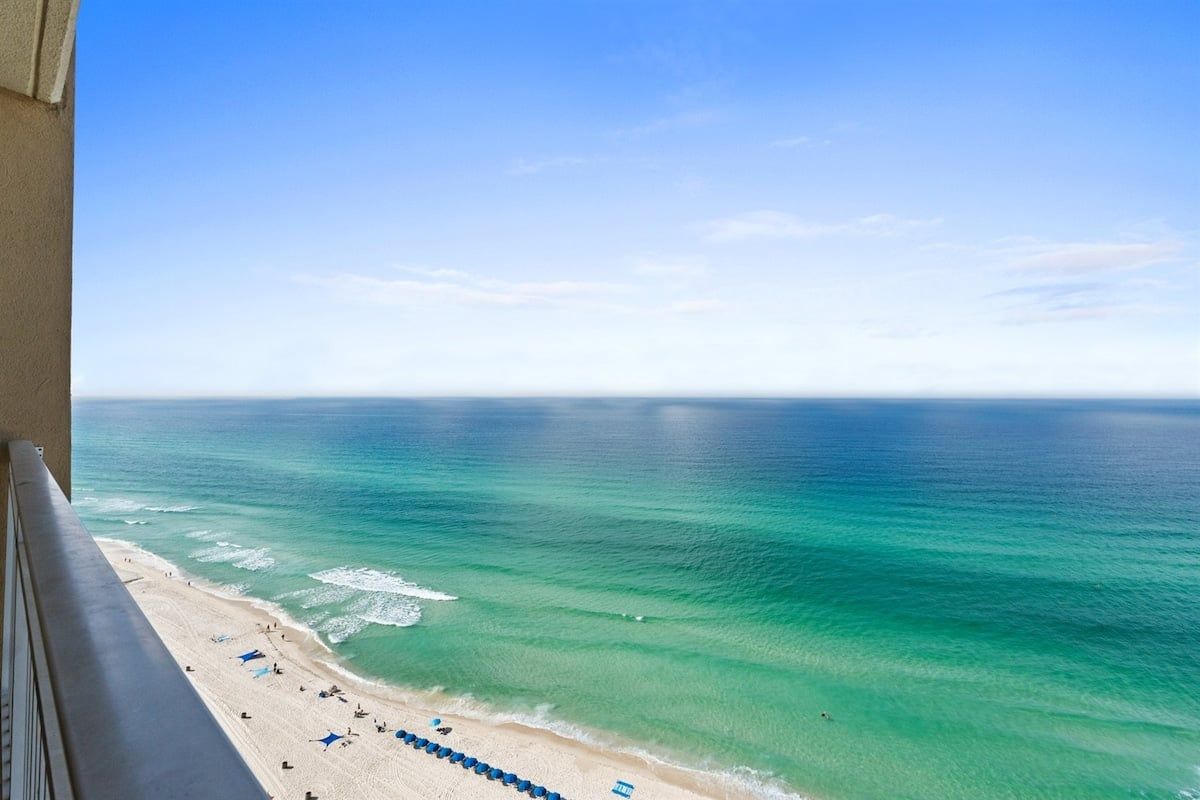 Ein Strand mit klarem türkisblauem Wasser und Meerblick vom Balkon.