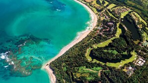 Vista aérea de una zona costera con playa, campo de golf y edificios residenciales.