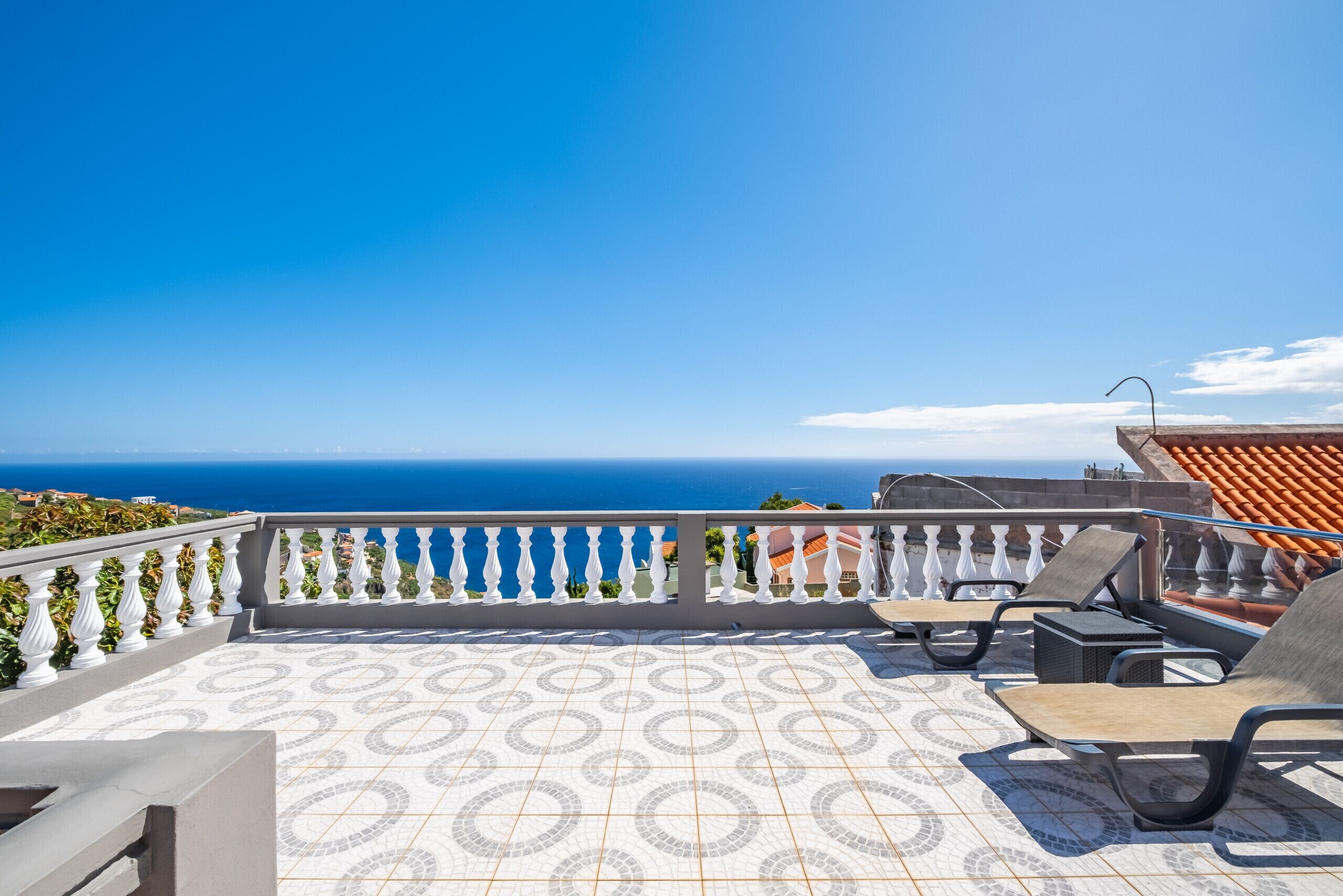 Une terrasse dotée d’un sol à motifs, d’une balustrade et offrant une vue sur la mer.