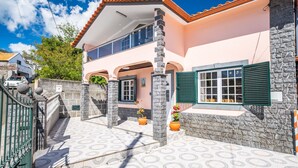 Una casa de dos pisos con fachada de piedra, un balcón y un patio adoquinado.