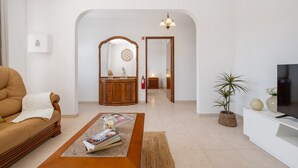 Una sala de estar con sofá, mesa de centro, televisor y planta en maceta.