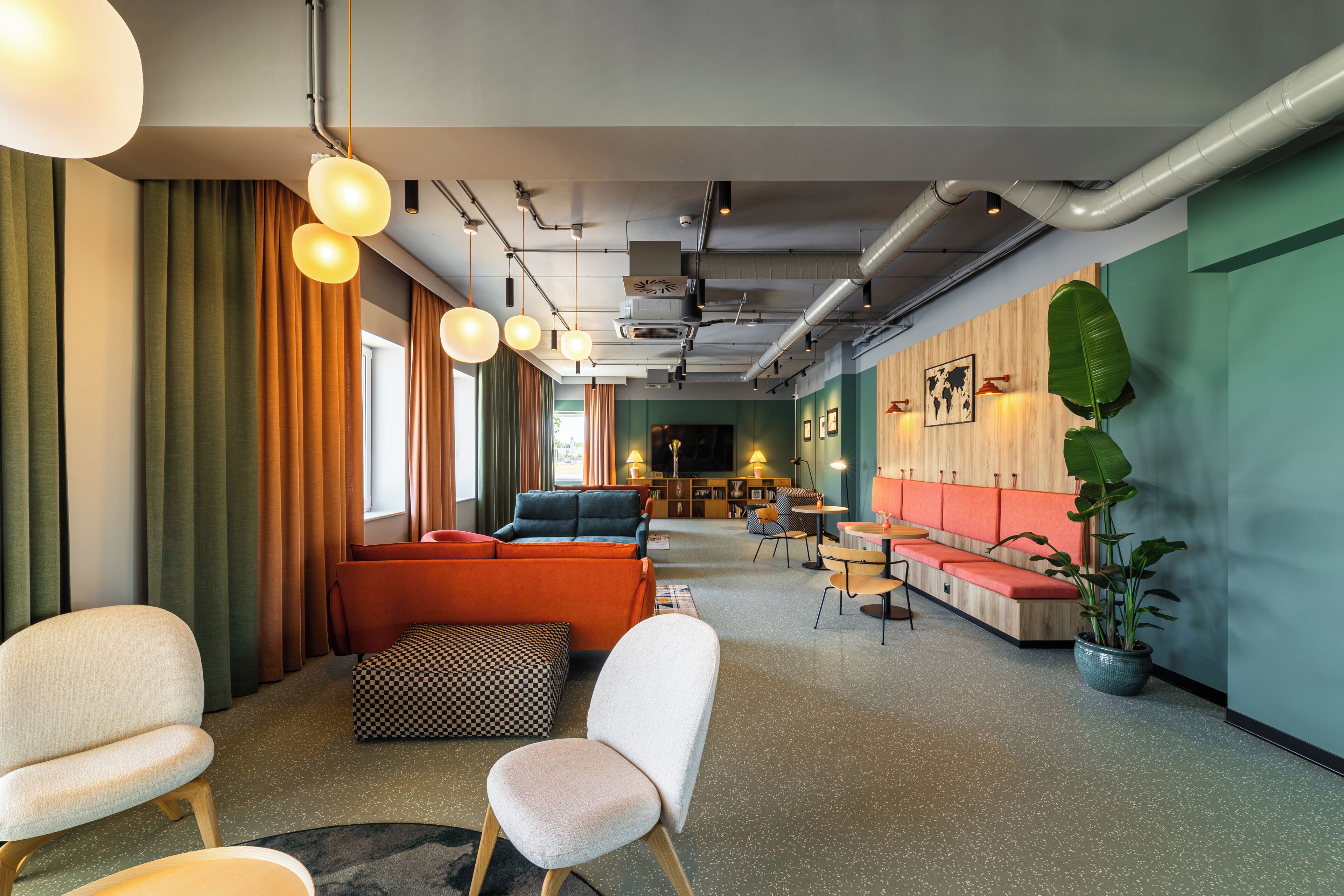 A modern lounge area with seating, a television, and a potted plant.