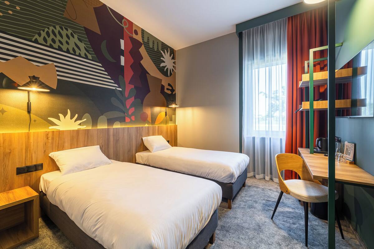 Une chambre d’hôtel avec deux lits, un bureau, une chaise et une bibliothèque.