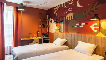 Habitación de hotel con dos camas, un escritorio y una pared decorada con arte abstracto.