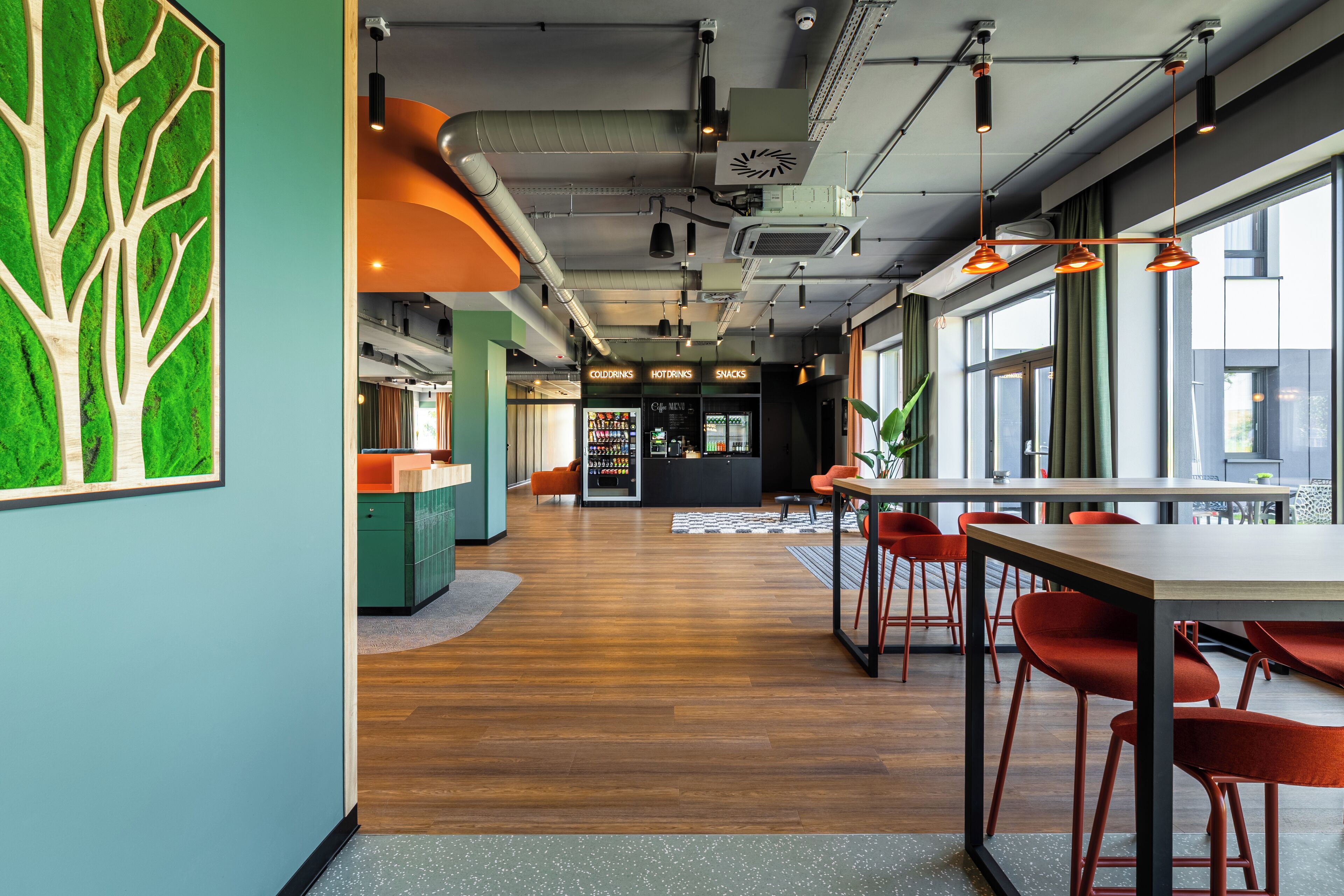 Een modern interieur met een houten vloer, een receptiebalie en oranje stoelen.