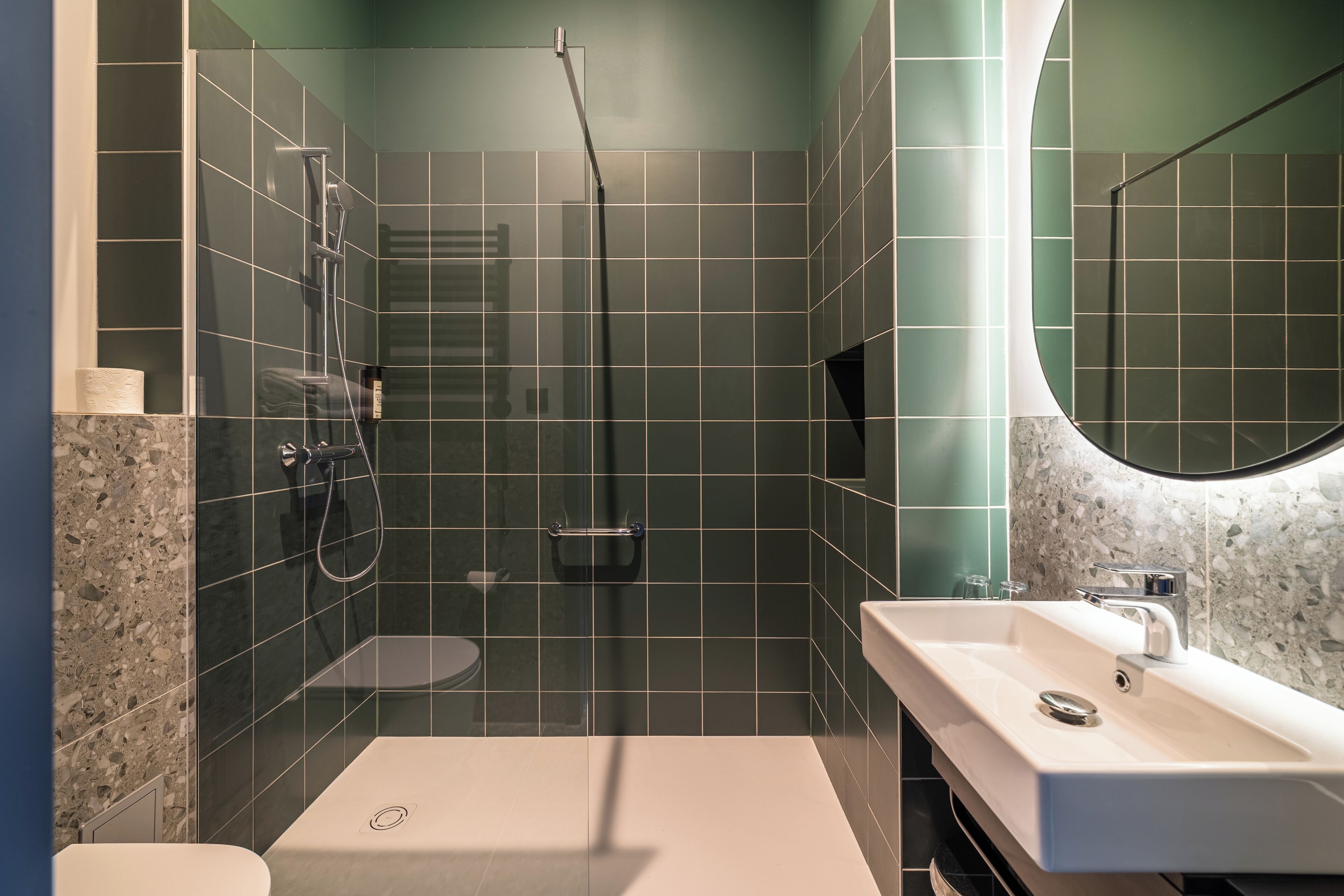 A modern bathroom with a glass-enclosed shower, a white sink, and a marble countertop.