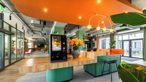 Un espace de bureau moderne avec un comptoir d’accueil en bois, un mur d’accent vert et une grande fenêtre laissant entrer la lumière naturelle.