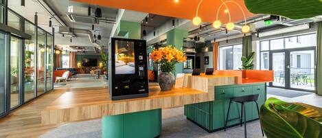 A modern office space with a wooden reception desk, a green accent wall, and a large window providing natural light.