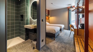 Une chambre d’hôtel moderne équipée d’une douche, d’un lavabo, d’un lit et d’un bureau.
